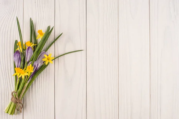 Narcisi e crochi sul vecchio tavolo di legno bianco . — Foto Stock