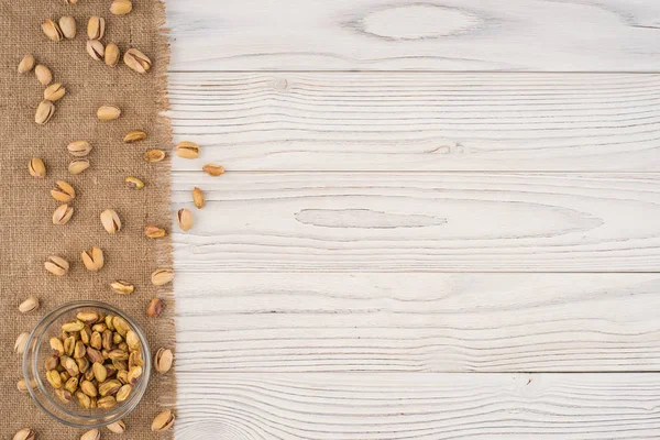 Pistazienkerne in einer Glasschüssel auf einem alten weißen Holztisch. — Stockfoto