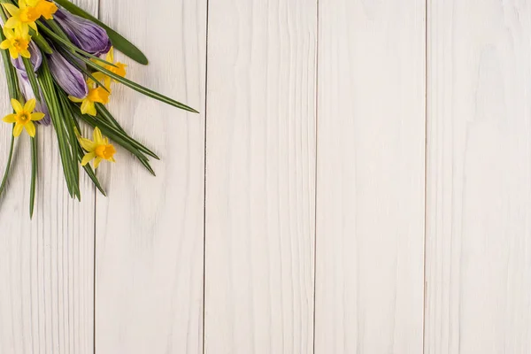 Narcisi e crochi sul vecchio tavolo di legno bianco . — Foto Stock