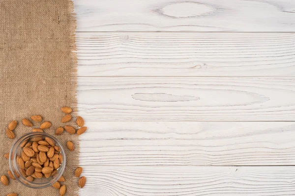 Almonds in a glass bowl and old white wooden table. — Stock Photo, Image