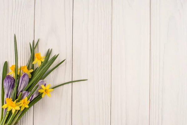 Narcisi e crochi sul vecchio tavolo di legno bianco . — Foto Stock