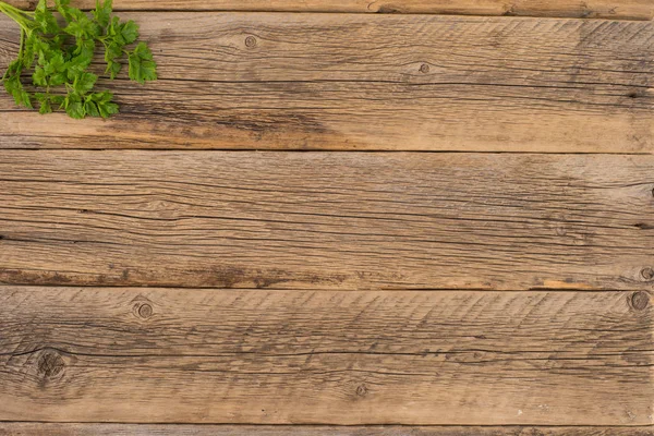 Una ramita de perejil sobre una vieja mesa de madera . —  Fotos de Stock