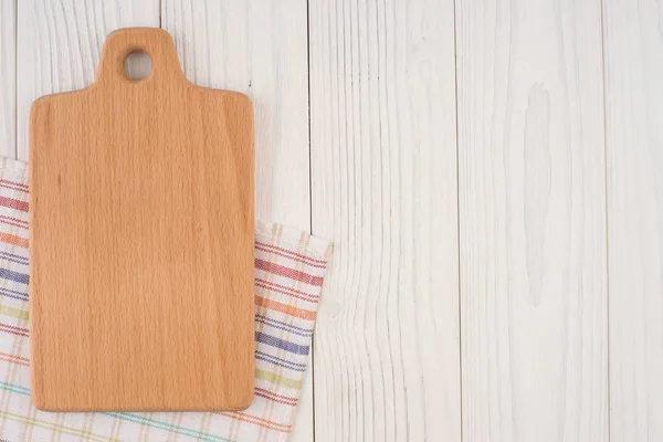 Tábua de corte em um guardanapo de cozinha na velha mesa de madeira . — Fotografia de Stock