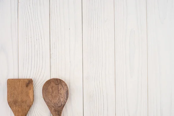 Cuchara de madera y espátula sobre una vieja mesa blanca . — Foto de Stock