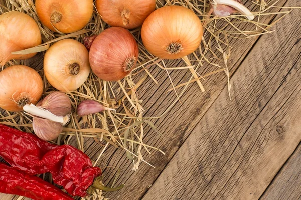Onions, garlic and pepper on old wooden table. — Stock Photo, Image