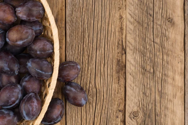 Eski ahşap masa sepetteki Erik. 