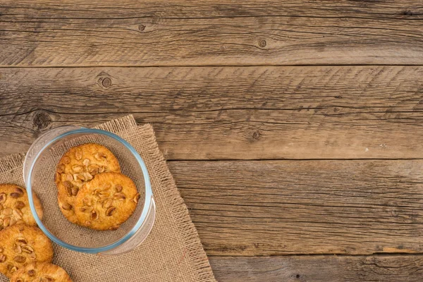 Galletas de cacahuete en un tazón de vidrio sobre una mesa de madera vieja . — Foto de Stock