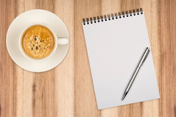 Coffee cup, spiral notebook and pen on the wooden table Royalty Free Stock Images