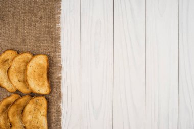 Çuval bezi ve Beyaz ahşap bir masa üzerinde kızarmış ekmek. 