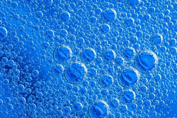 Grote prachtige zuurstofbellen onder water op een blauwe achtergrond macro. — Stockfoto