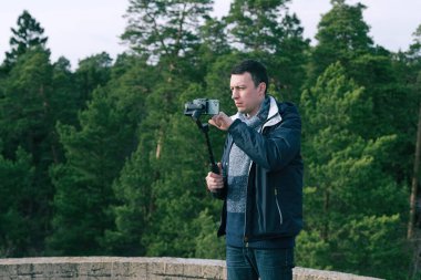 Erkek turist telefon için dengeleyici kullanıyor ve doğayı vuruyor