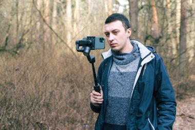 Erkek turist telefon için dengeleyici kullanıyor ve doğayı vuruyor