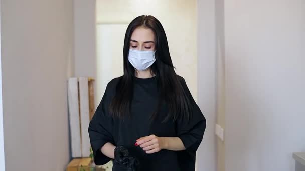 Молодая брюнетка носит черные перчатки для защиты от вируса во время эпидемии 2020 года — стоковое видео