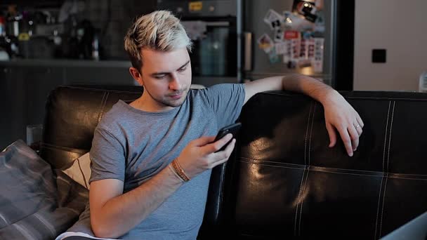 Un hombre joven utiliza su teléfono inteligente, pasa por la pantalla — Vídeos de Stock