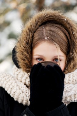 Dışarıda sıcak içecek içen bir kadın.