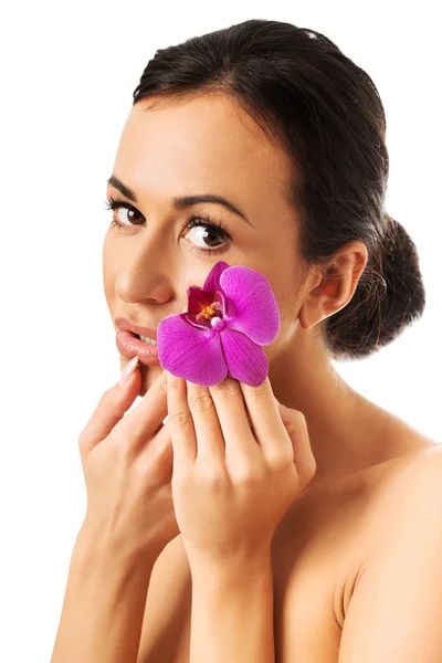 Mulher com pétala de orquídea roxa perto do rosto — Fotografia de Stock