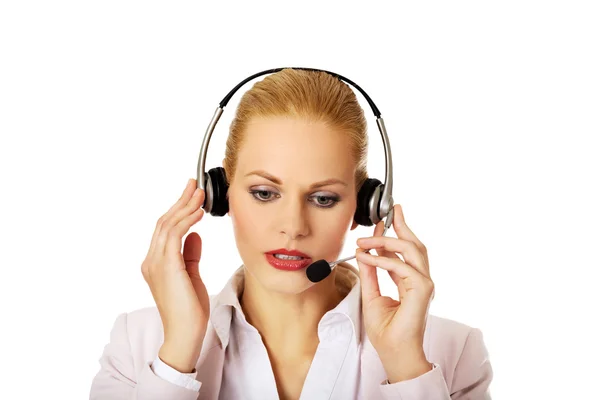 Mujer joven operador de línea de ayuda está tratando de escuchar algo a través de los auriculares —  Fotos de Stock
