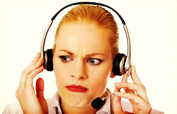 Mujer joven operador de línea de ayuda está tratando de escuchar algo a través de los auriculares — Foto de Stock