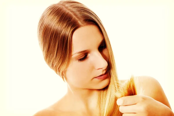 Mulher chocada mostrando suas pontas duplas danificadas de cabelo . — Fotografia de Stock