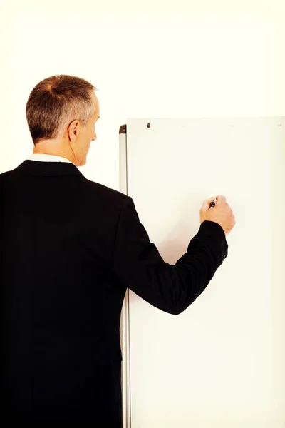 Male executive writing on a flipchart — Stock Photo, Image