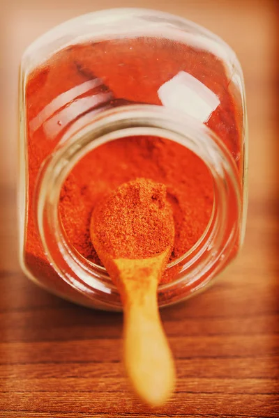 Paprika specerij in glazen pot met houten lepel — Stockfoto