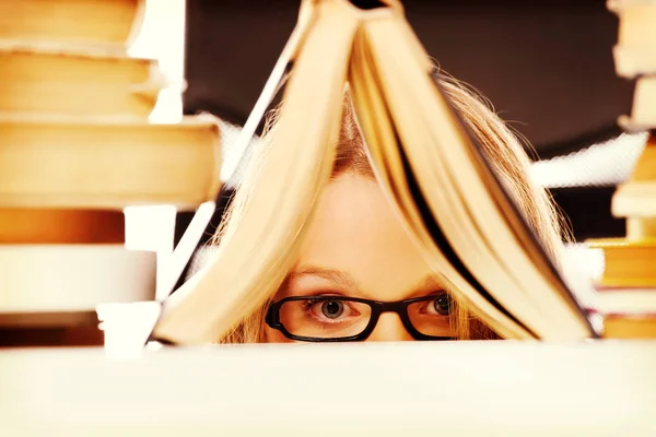 Молода жінка ховається за книгою — стокове фото