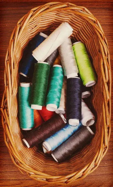 Bobbins thread in willow basket on wooden background — Stock Photo, Image