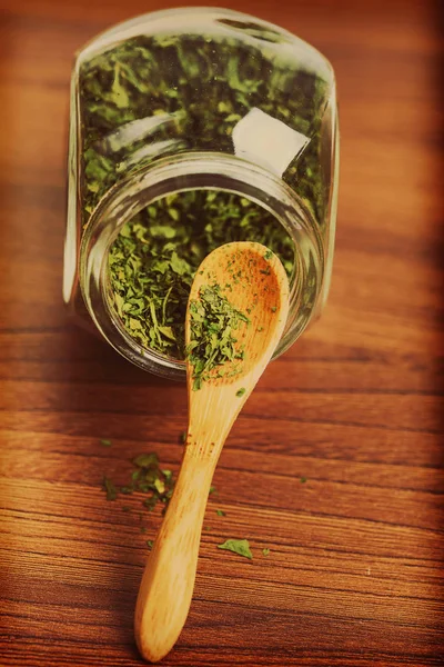 Dry parsley in glass jar with wooden spoon — Stock Photo, Image