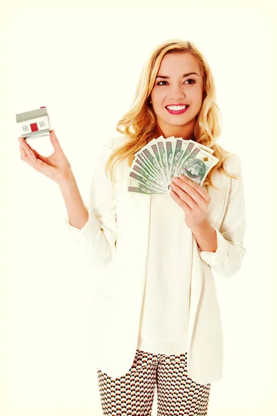 Mulher atraente mostrando notas de dólar e casa pequena . — Fotografia de Stock