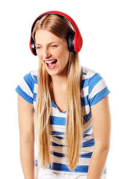 Giovane donna con cuffie che ascolta e canta musica, isolata su bianco — Foto Stock