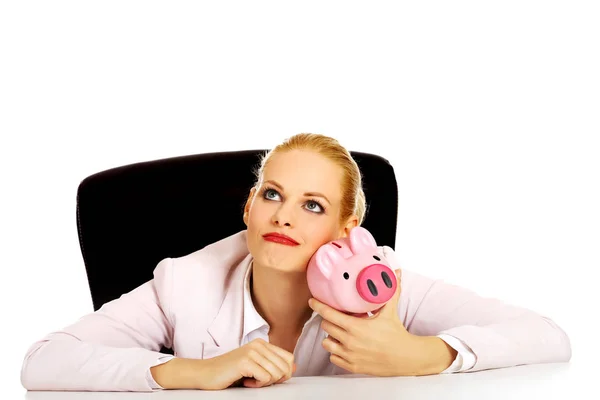 Mujer de negocios feliz con una hucha detrás del escritorio —  Fotos de Stock