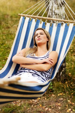 Genç sarışın kadın hamakta dinleniyor.