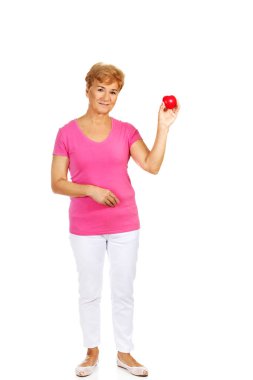 Kırmızı oyuncak kalp tutan eski gülümseyen kadın