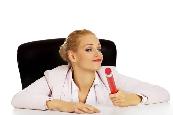 Junge Geschäftsfrau sitzt hinter dem Schreibtisch und hält großen Stift — Stockfoto