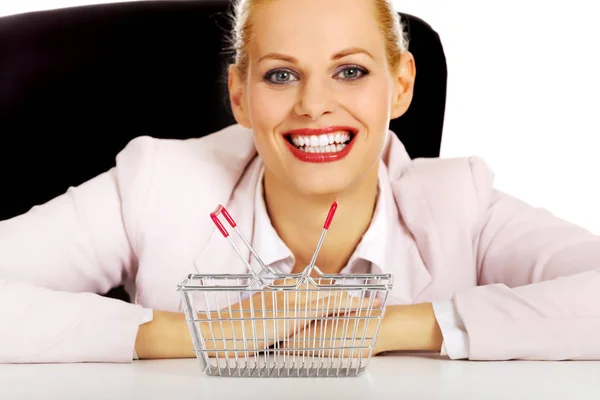 Улыбающаяся деловая женщина, сидящая за столом с маленькой корзинкой — стоковое фото