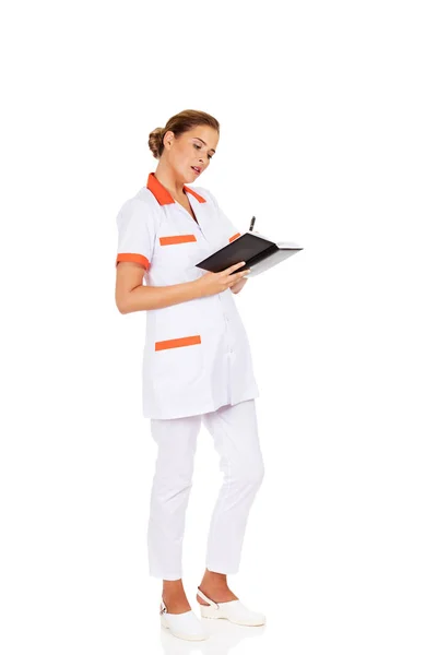 Jovem foco médico ou enfermeiro feminino faz anotações — Fotografia de Stock