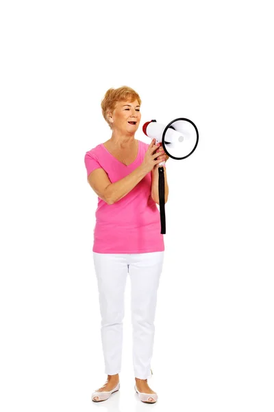 Senior lachende vrouw schreeuwen via een megafoon — Stockfoto