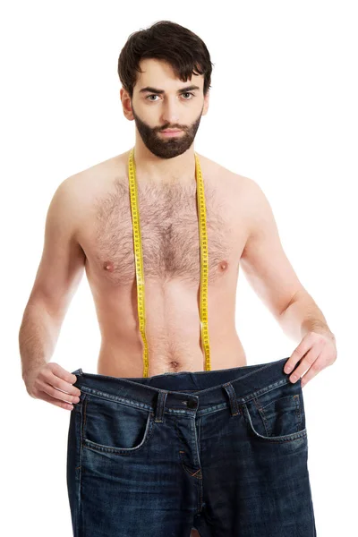 Человек с огромными джинсами и лентой для измерения . — стоковое фото