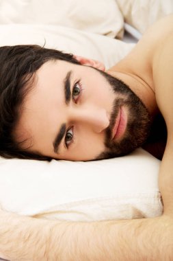 Genç kaslı adam yatakta yatıyor..