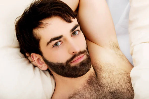 Młody muskularny mężczyzna leży w łóżku. — Zdjęcie stockowe