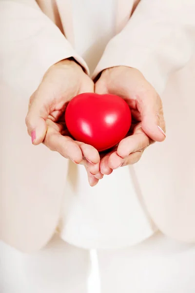 Donna anziana che tiene il modello di cuore su palme aperte — Foto Stock