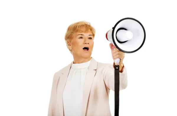 Senior lachende vrouw schreeuwen via een megafoon — Stockfoto