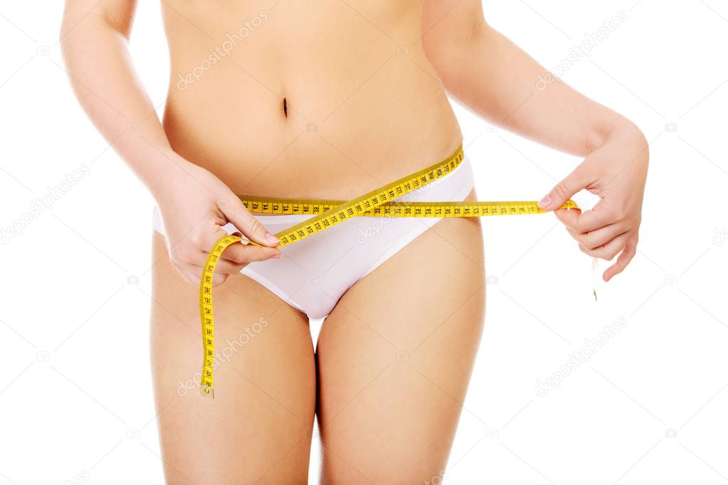 Beautiful slim woman measuring her hips