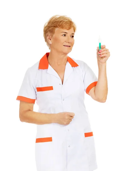 Sonríe anciana doctora o enfermera sostiene jeringa — Foto de Stock