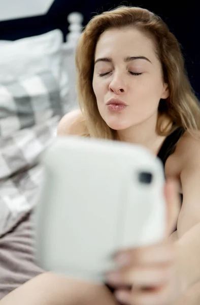 Menina bonita fazendo selfie na cama com câmera instantânea — Fotografia de Stock