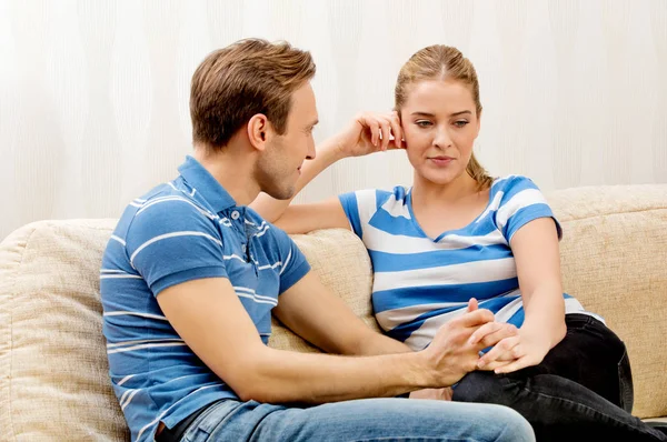 Feliz pareja cogida de la mano y sentada en un sofá — Foto de Stock