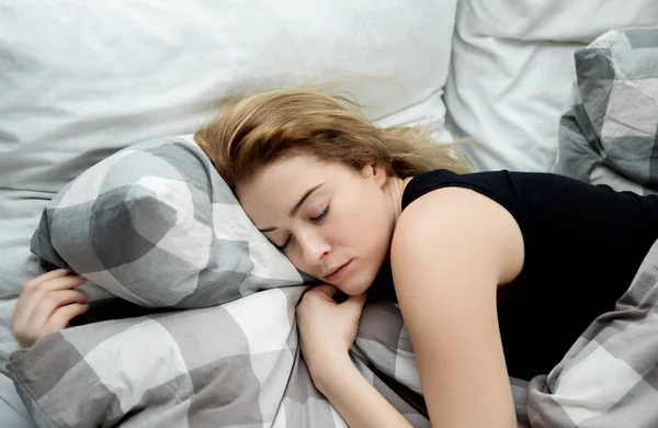 Ung kvinna sover i sin säng. — Stockfoto