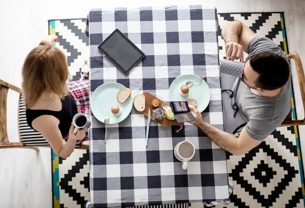 Любящая пара, сидящая за кухонным столом, завтракающая вместе — стоковое фото
