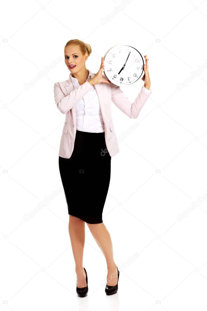 Smiling young business woman holding office clock