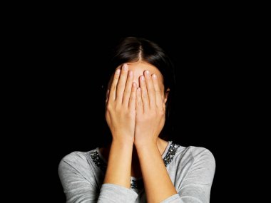 Genç bir kadın elleriyle yüzünü kapatıyor.